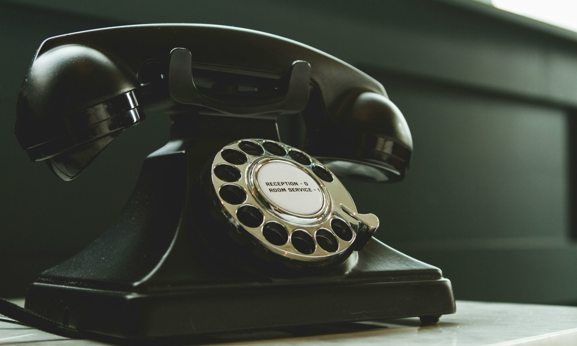 Classic black rotary phone on hotel reception desk, evoking nostalgia and vintage charm.